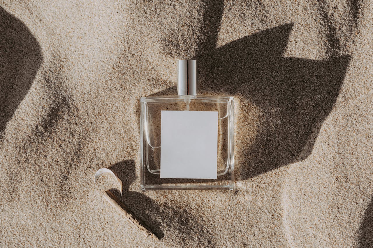 Elegant perfume bottle casting shadows on sand, ideal for beauty product concepts.