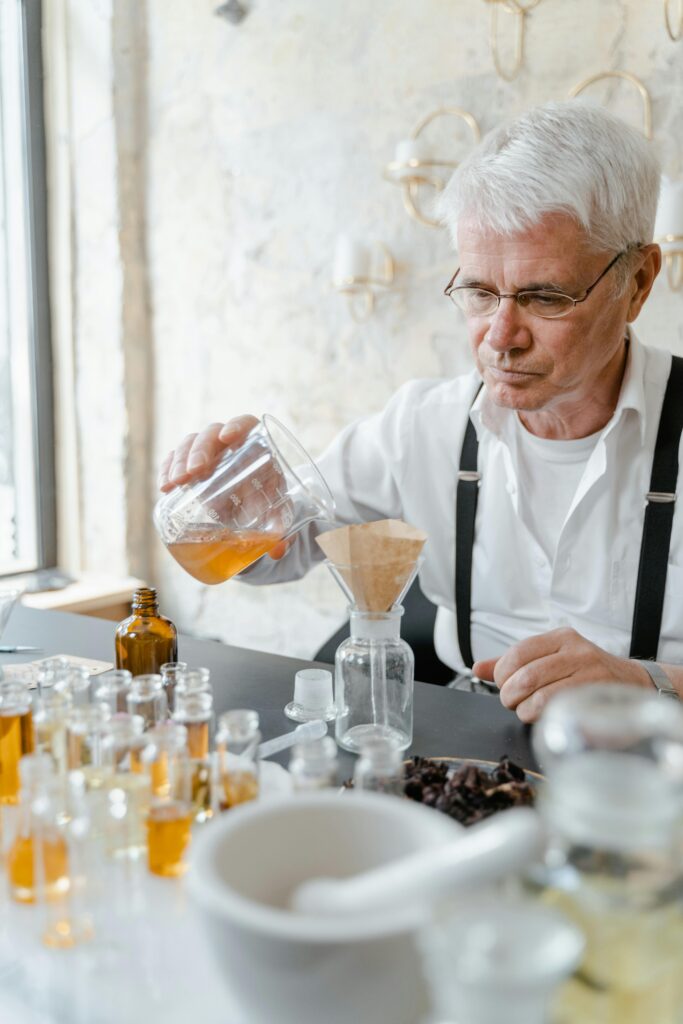 pexels-photo-8450108-8450108 Elderly man mixing liquids for perfume creation in an indoor workspace.
